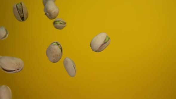 Closeup of the Salted Pistachios Falling Diagonally on a Yellow Background