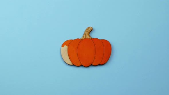 Halloween Stop-Motion wooden painted pumpkin on a blue themed background, top view.