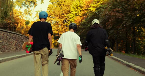 Group of Friends Skate at Sunset. The Boys Walk with Skates in Their Hands.