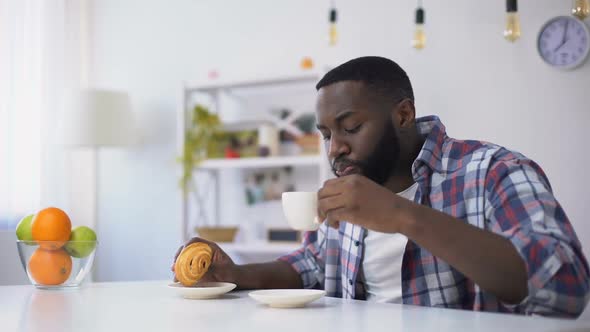 Black Man Eating Croissant With Coffee, Feeling Tooth Ache From Sweet Food