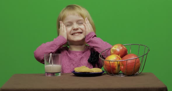 Girl Sitting at the Table and Eating Chocolate, Cookies and Drinks Cacao