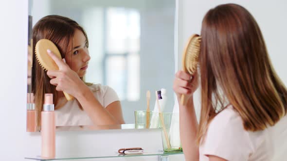 Teenage Girl Brushing Hair with Comb at Bathroom