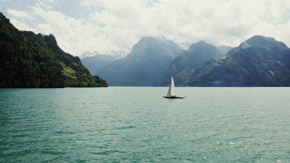 A Sailboat Floats on a Picturesque Lake at the Foot of the Alpine Mountains