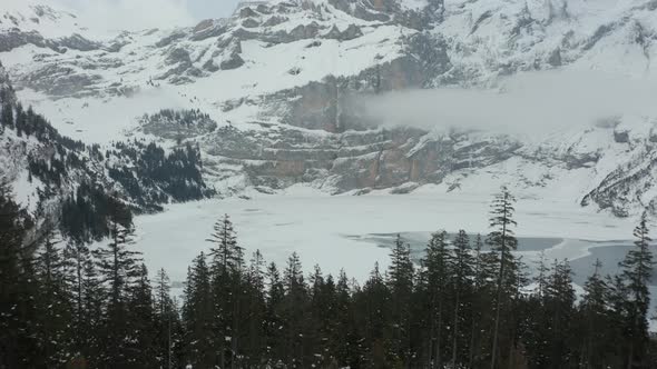 Flying over green forest and revealing frozen lake in wilderness