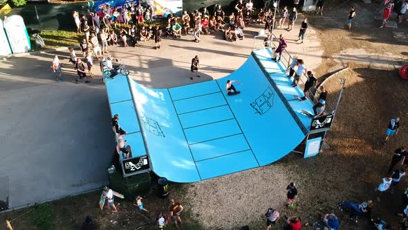 Male skateboarder doing tricks in an outdoor mini-ramp contest.