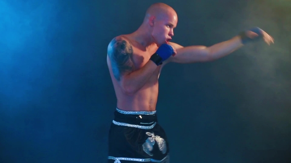 Muscular Kickbox Or Muay Thai Fighter Punching In Smoke.