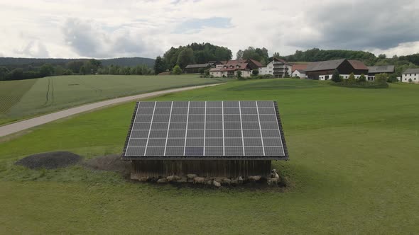 Sheep graze on a field near a barn with solar panels