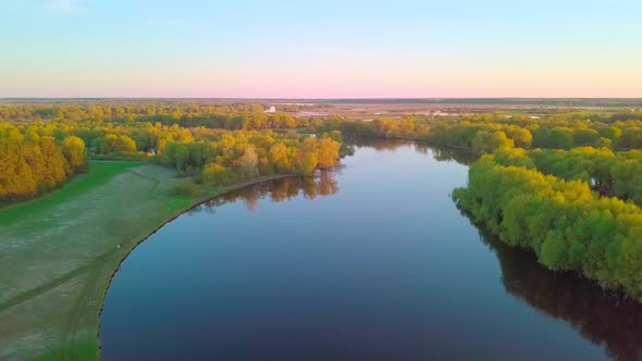 The Drone Flies Over a Beautiful Summer Landscape with a River at Sunset