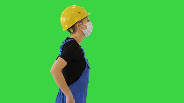 Female Construction Worker in Overalls and in Medical Mask Walking on a Green Screen, Chroma Key.