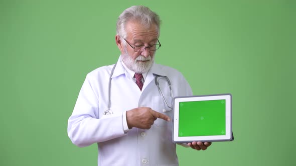 Handsome Senior Bearded Man Doctor Against Green Background