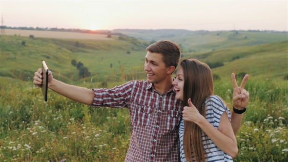 Attractive Young Girl and The Guy Taking Selfie at Sunset. 