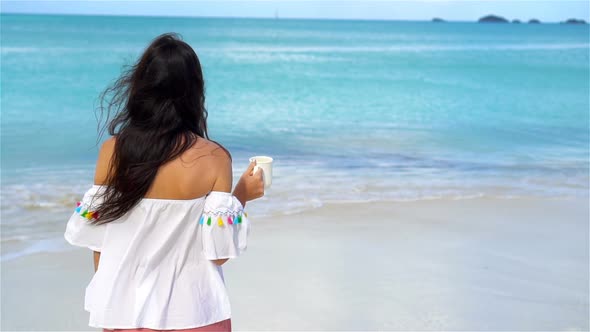 Young Woman with Hot Coffee Enjoying Beach View. Beautiful Girl in Slow Motion Video