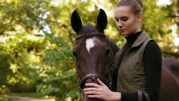 Closeup View of Young Beautiful Woman Petting Brown Horse While Standing in the Green Field
