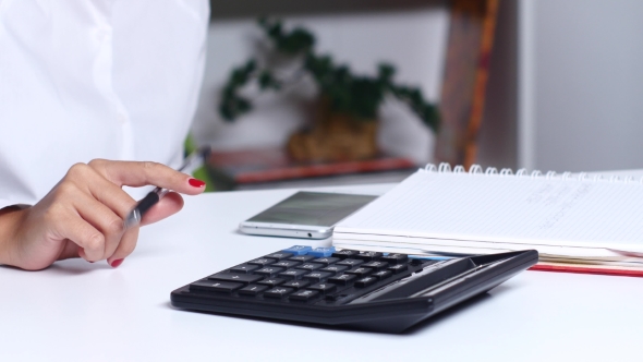 Woman Doing Calculations In The Office And Writes Resulting Numbers. 