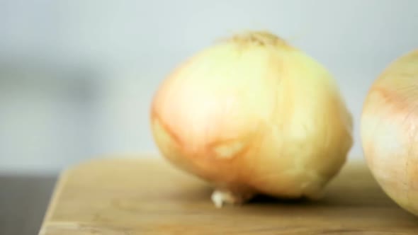 Step by step. Slicing yellow onion with kitchen knife on a cutting board.