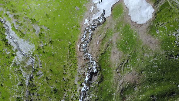 Aerial: drone flying over scenic waterfall and mountain stream on the italian Alps