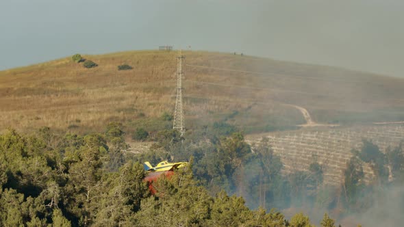 Fire fighter plane drops fire retardant on a forest fire in the hills