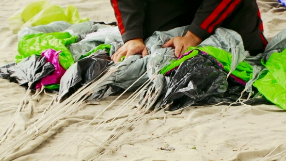 Man Wrapping Parachute Shroud Lines On The Ground