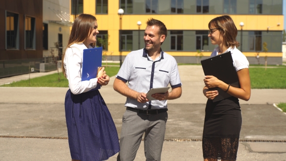 Three Students Are Walking Through Campus And Communicate