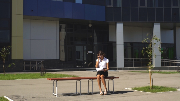 Businesswoman Sitting on a Bench at Lunchtime And Talking on the Phone