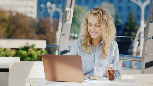 Young Business Woman Working In a Cafe With a Laptop, Eat Ice Cream. On The Summer Terrace Of a Cafe