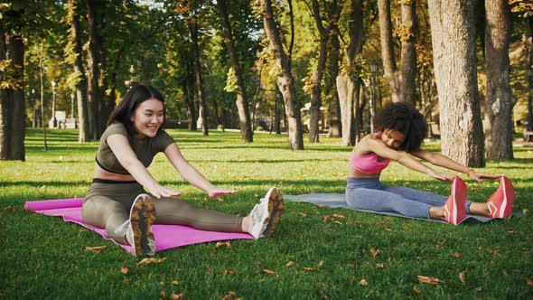 Happy Diverse Women Practicing Stretching Training Sitting on Fitness Mats Outdoor Slow Motion