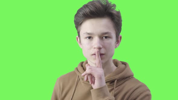 Close-up of Serious Teenager Making Hush Gesture and Looking at Camera. Portrait of Brunette