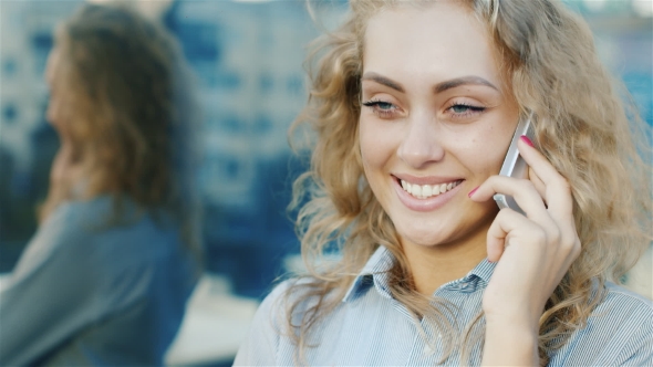 Portrait of Attractive Woman Talking on the Phone. Smiling, the Wind Blowing in Her Hair