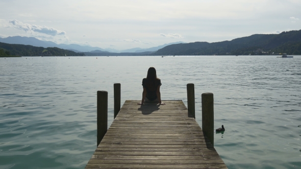 Relaxation at Mountain Lake. Woman Sits on Dock