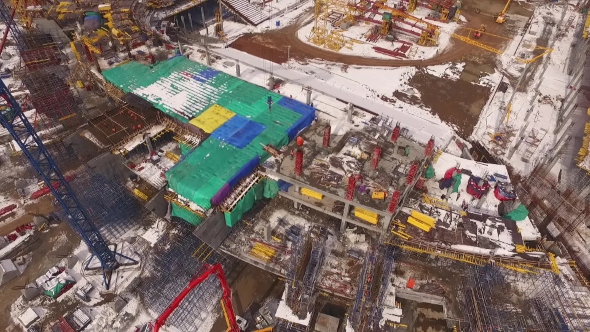 Aerial Top View Of Stadium Construction, Moving Construction Materials By Huge Crane, Winter Time