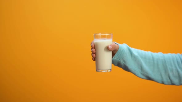 Woman Hand Taking Offered Glass of Milk on Bright Background, Morning Energy