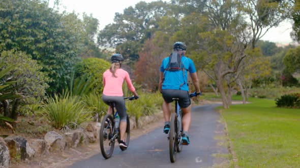 Couple cycling on the road in park