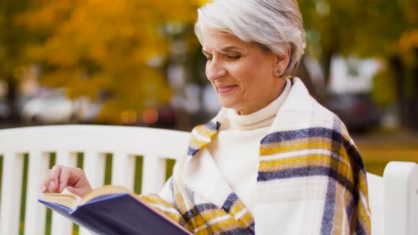 Happy Senior Woman Reading Book at Autumn Park 32
