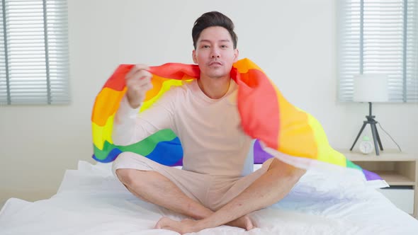 Portrait of Asian young handsome male gay holding LGBT flag and smile.