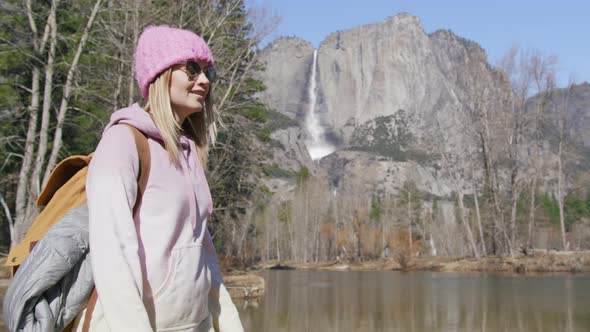 Side View of Woman in Pink Hat Traveling By Autumn Pine Forest with a Backpack