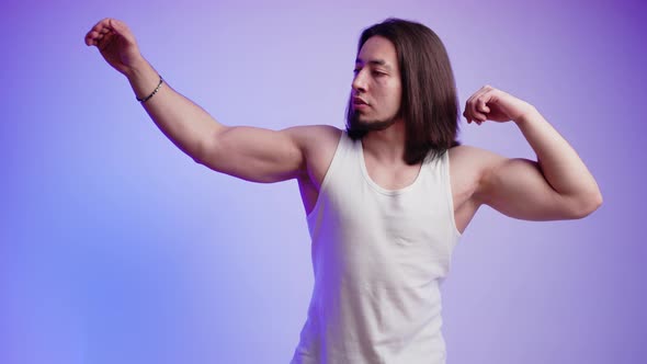 Medium Studio Shot of Caucasian Muscled Bodybuilder Man Posing and Tightening His Muscles