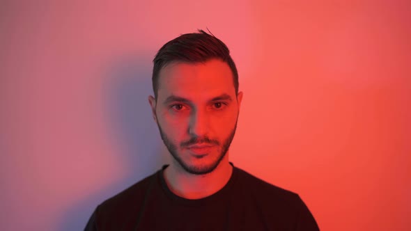 Young Man with Black Shirt Putting Black Face Mask Against Red Background