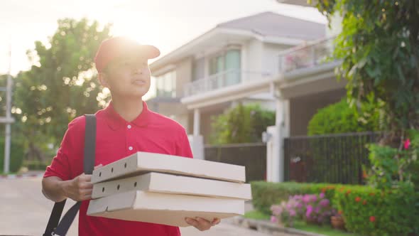 Asian deliver man worker in red color uniform handling bag of food, pizza give to customer girl.