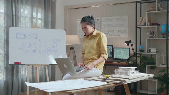 Asian Woman Engineer Sitting On The Table And Using A Laptop To Work At The Office alt