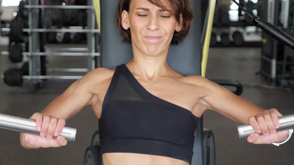 Beginner in Sports Woman Is Working Out First Time on a Simulator for the Arms Muscles. Newcomer in