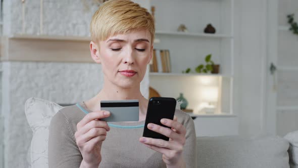 Woman Customer Holding Credit Card and Smartphone Sitting on Couch at Home
