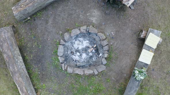 Burnt-out camping fireplace with ashes encircled by benches in Czechia.