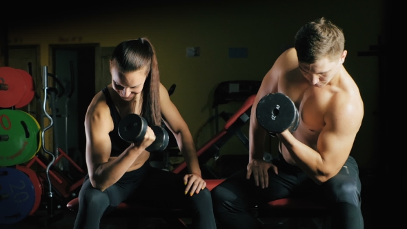 Man and Woman Working His Arms at the Gym.