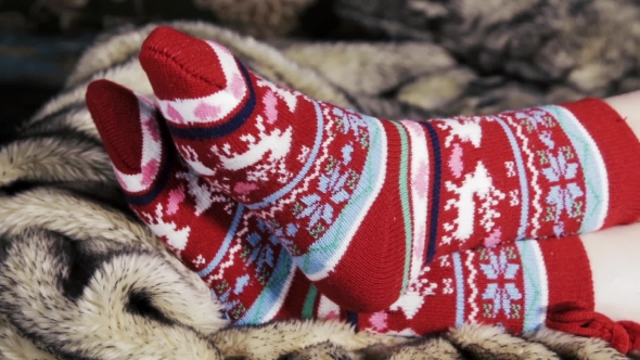 Female Legs In Christmas Socks Under a Blanket