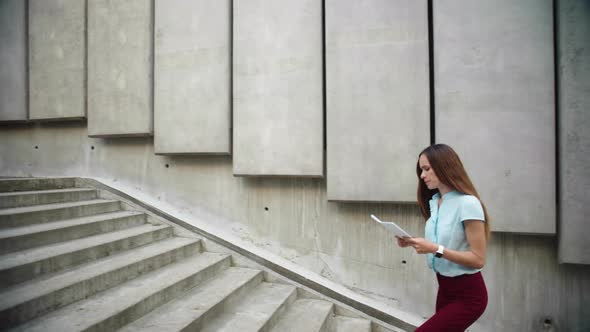 Businesswoman Reading Business Papers on Street. Attractive Woman Going for Job