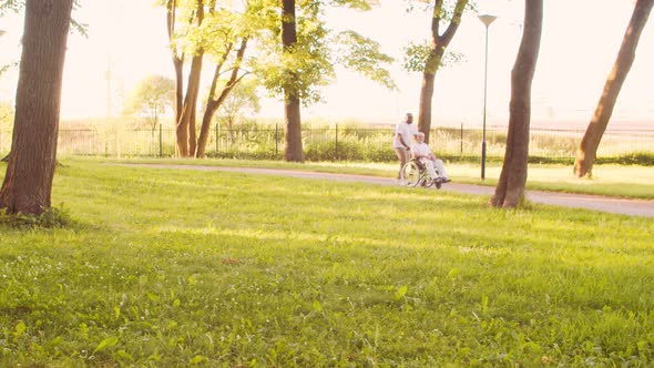 African-American caregiver and old disabled man in a wheelchair. Nurse and patient.