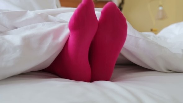 Female Legs In Pink Stockings On Bed