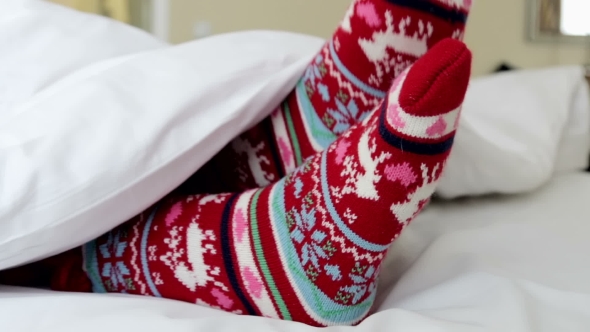 Female Legs In Christmas Socks In Bed