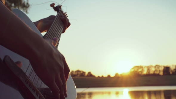 Of Girl's Hands Playing Guitar Near The Evening Pond.