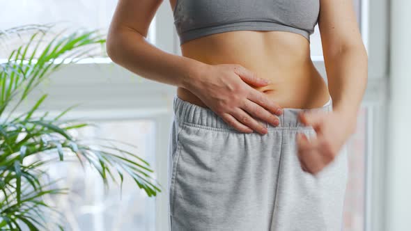 Woman Puts on Her Pants Strokes Her Stomach and Gives a Thumbs Up